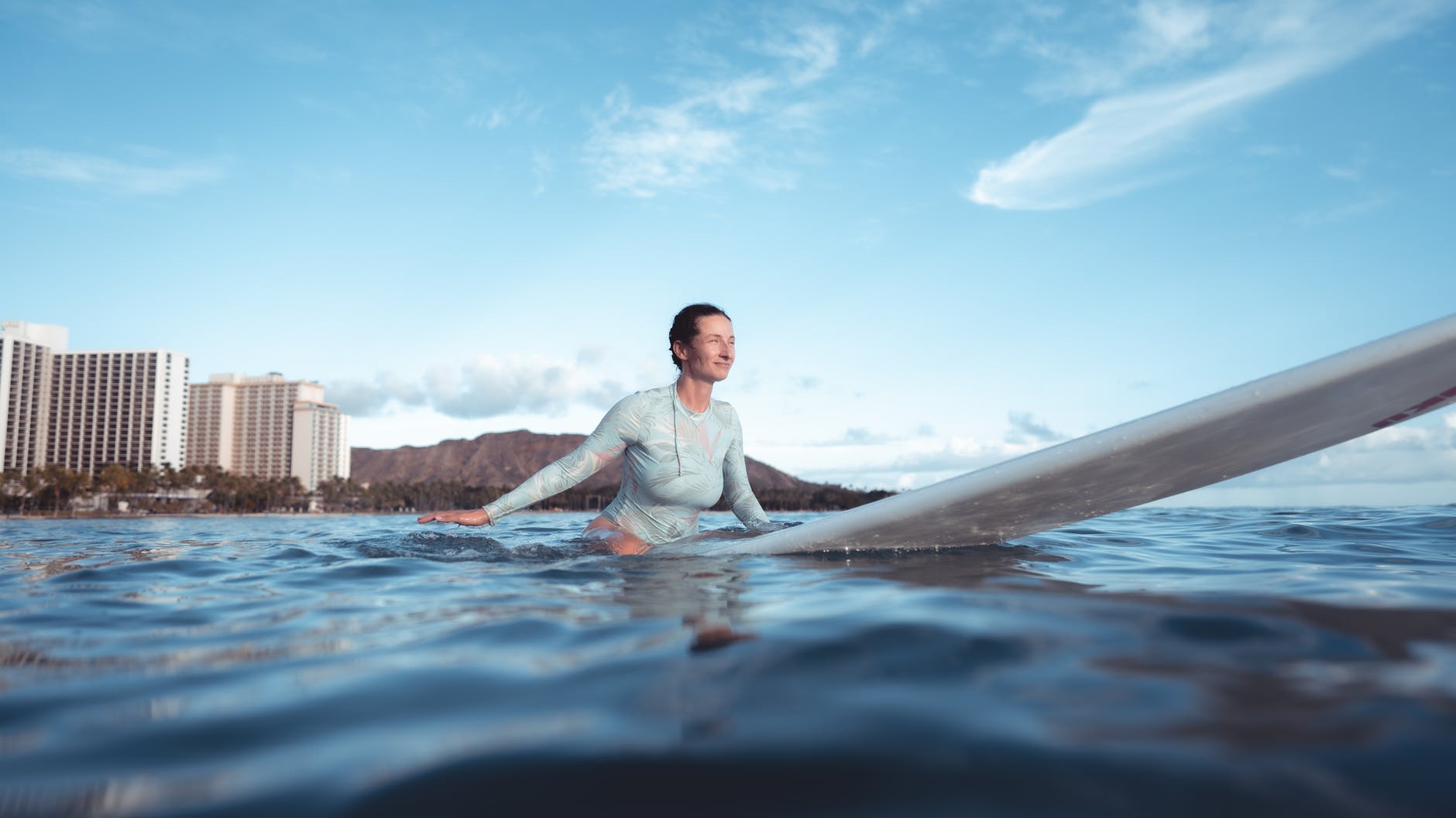 sporty young lady sitting on surfboard in ocean
