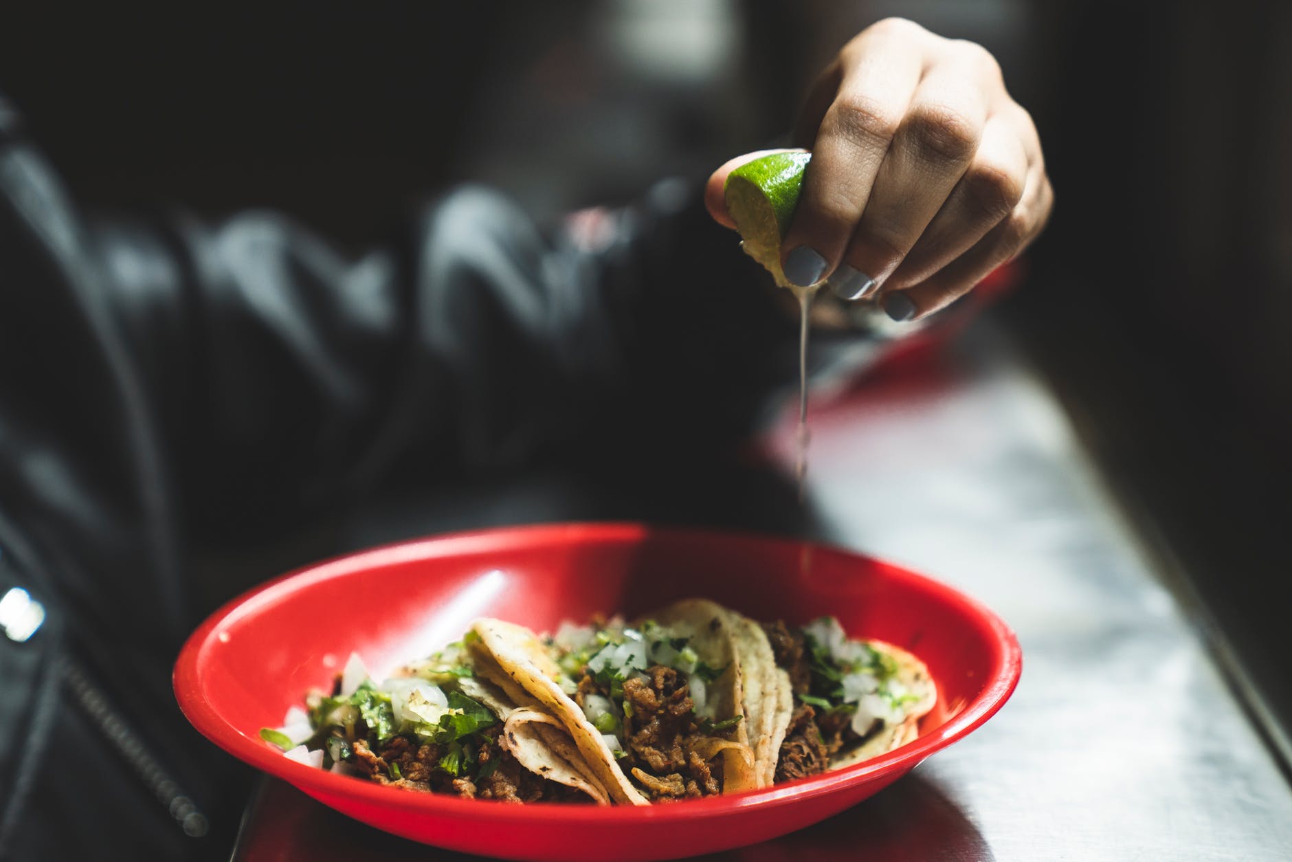 person squeezing lime on the tacos