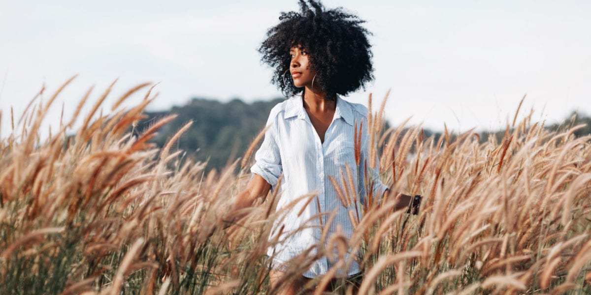 A young African American woman walks through a field at sunset © | Zolotarevs/Shutterstock