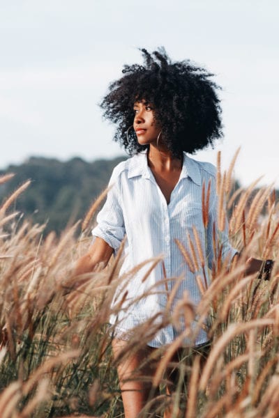 A young African American woman walks through a field at sunset © | Zolotarevs/Shutterstock