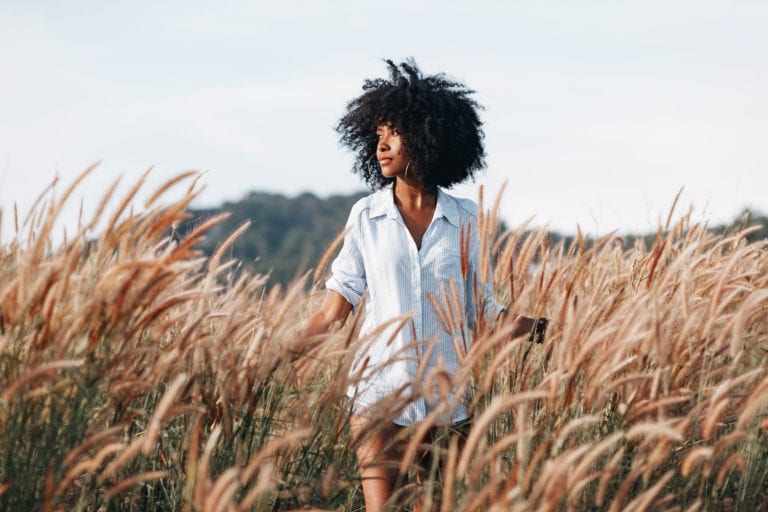 A young African American woman walks through a field at sunset © | Zolotarevs/Shutterstock