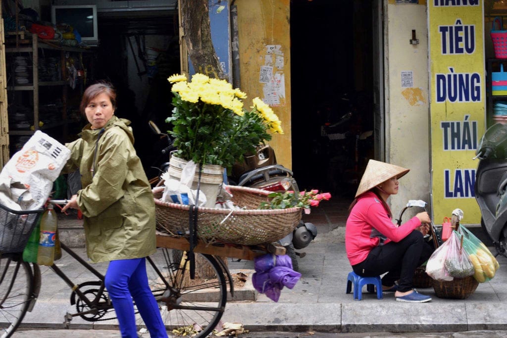 A local woman passes a sidewalk street vendor selling fresh food © | Nikki Vargas