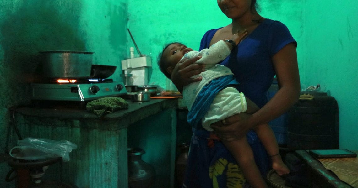 Vera* nurses her young daughter in her kitchen © | Jenna Kunze