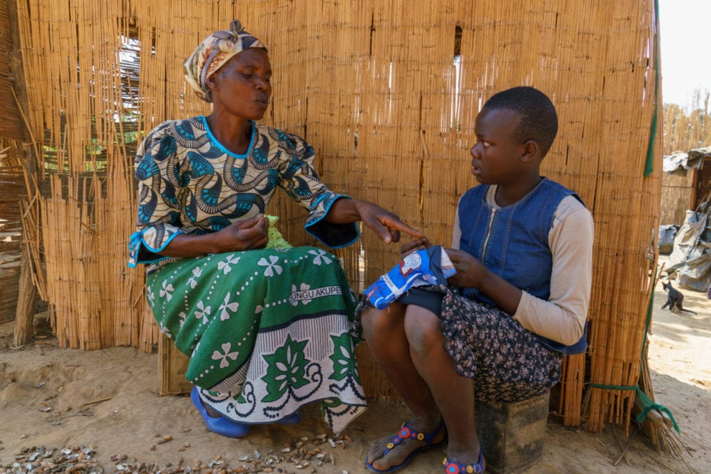 Elizerbeth, 54, teaching her grand-daughter, Mary how to make a sanitary cloth locally known as nyanda | © WaterAid/ Dennis Lupenga