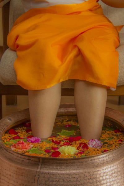 A client receives a flower-filled foot bath treatment. | © Moksha Ayurveda & Panchakarma Center