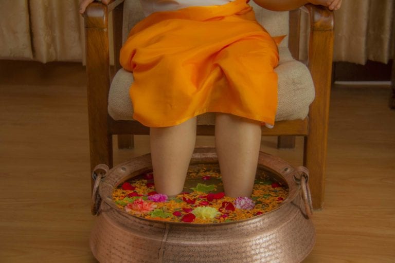 A client receives a flower-filled foot bath treatment. | © Moksha Ayurveda & Panchakarma Center