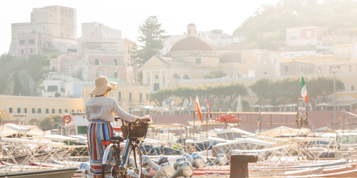 Young woman with bike at Ponza Island harbor pier in Italy | © WineDonuts/Shutterstock