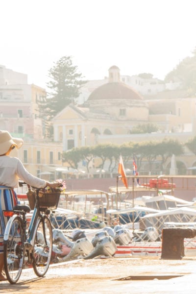 Young woman with bike at Ponza Island harbor pier in Italy | © WineDonuts/Shutterstock