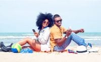 A happy young couple poses on the beach | © Akhenaton Images