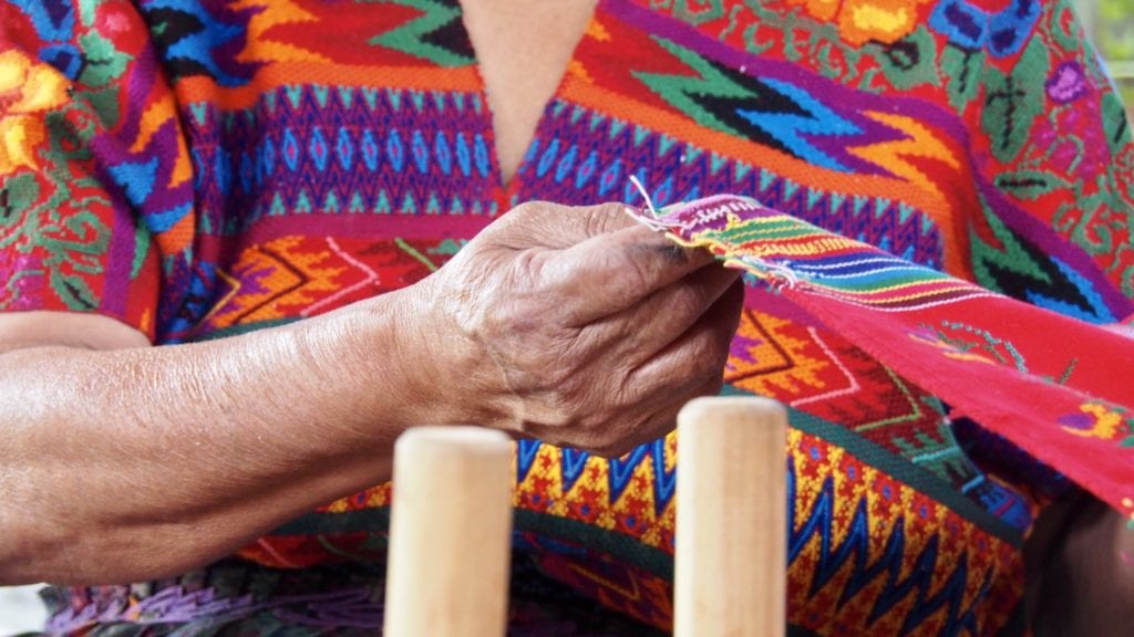 Dona Gloria holds up threads at Manos de Fe in Guatemala | © Nikki Vargas/Unearth Women