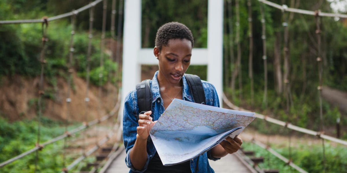 A solo black female traveler looks at a map | © Shutterstock