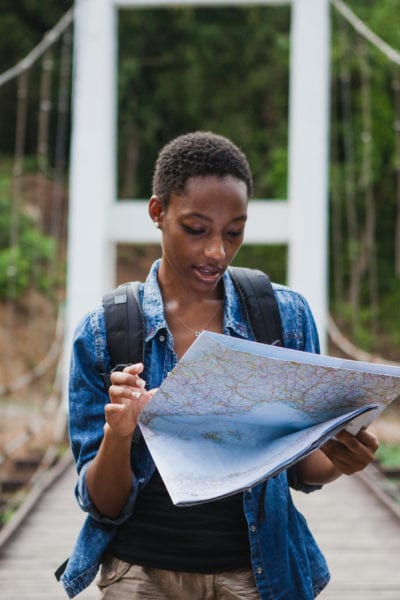 A solo black female traveler looks at a map | © Shutterstock