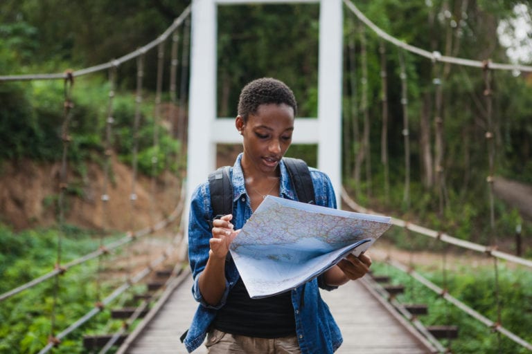 A solo black female traveler looks at a map | © Shutterstock