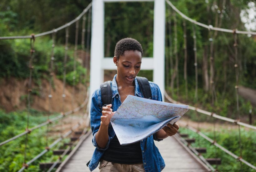 A solo black female traveler looks at a map | © Shutterstock