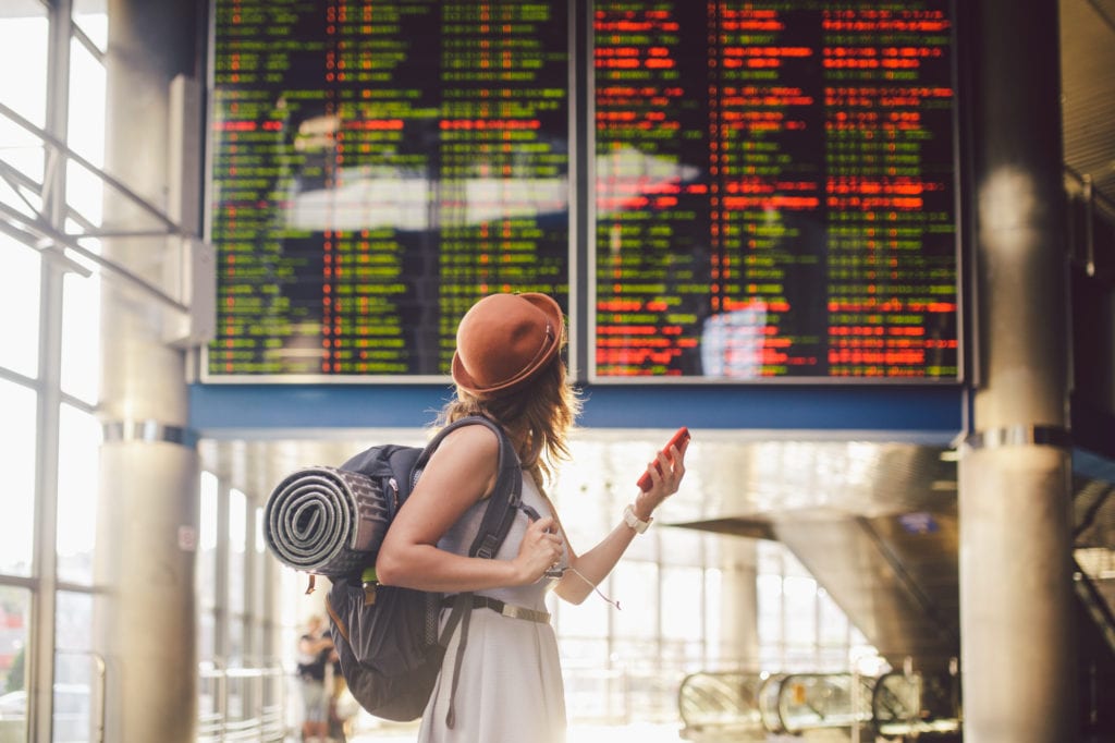 A solo female traveler looks at departure times at the airport | © Fotoliza/Shutterstock