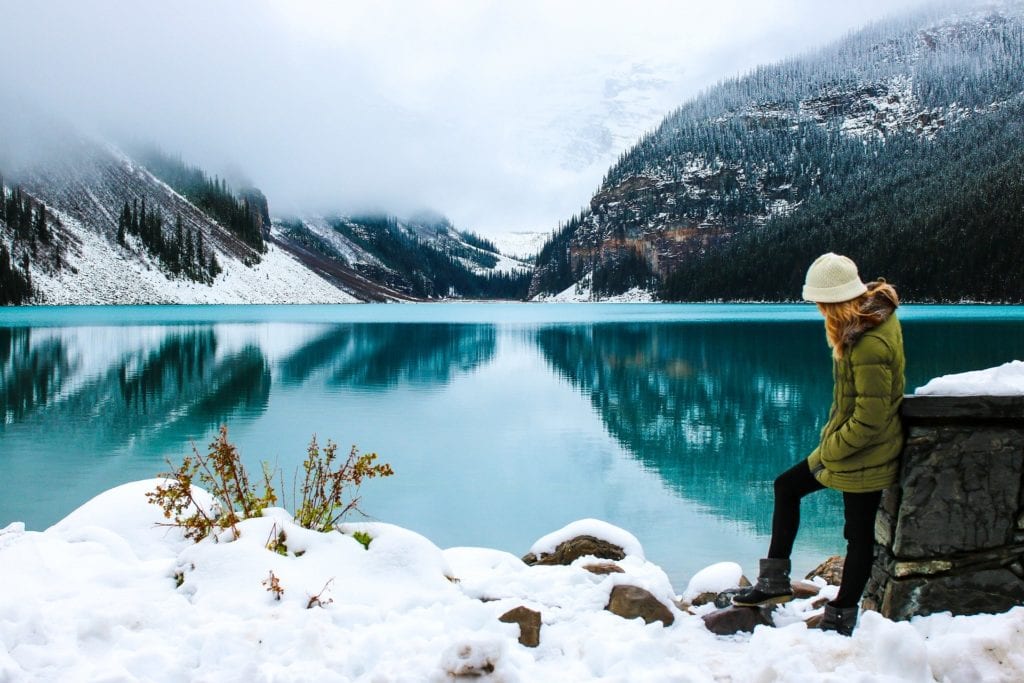 A solo female hiker in stands by a scenic lake | © Olya Adamovich/Pixabay