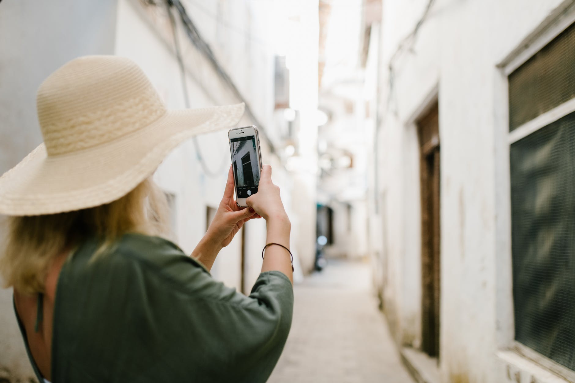 woman taking photo of building in alley